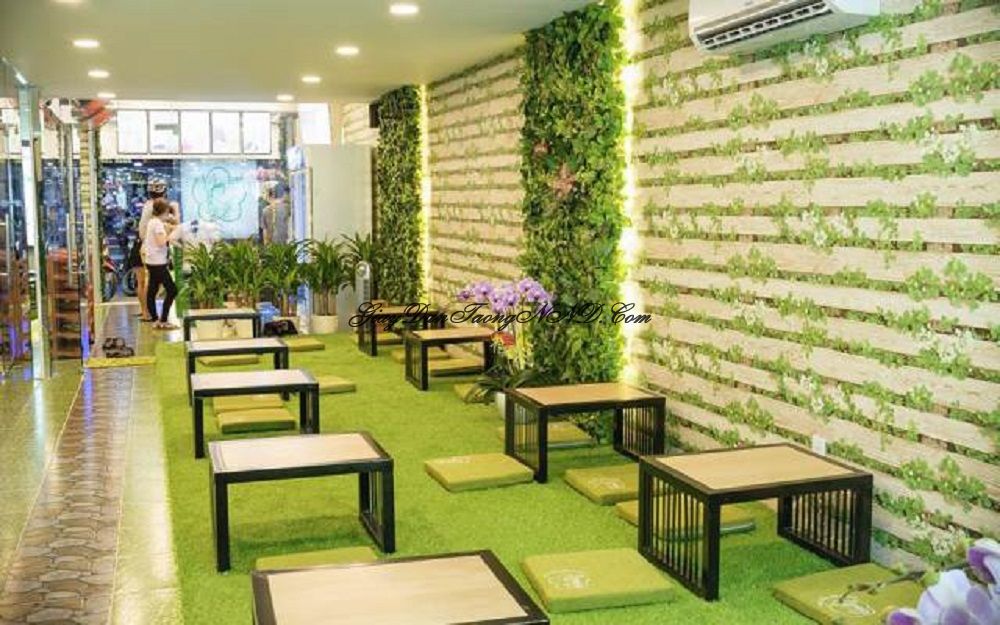 Giấy dán tường giả gỗ mã 87020-2 hình cây dây leo xanh, kết hợp với cây dán tường và thảm trải sàn đồng bộ màu xanh tạo cho không gian quán một cảm giác gần gũi với thiên nhiên